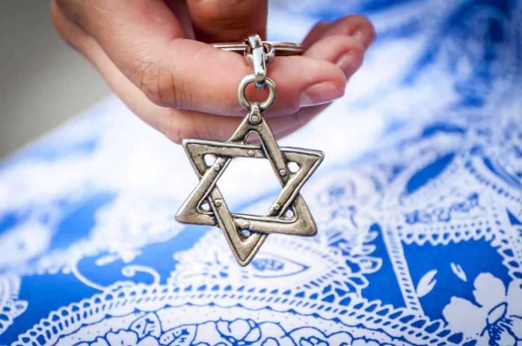 Young woman's hand holding a Star of David - Magen David key chain. The State of Israel, Holocaust remembrance, Judaism, Zionism concept image.