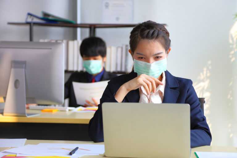 Employees working in business office while wearing medical face mask for protecting and preventing the infection of corona virus or covid-19