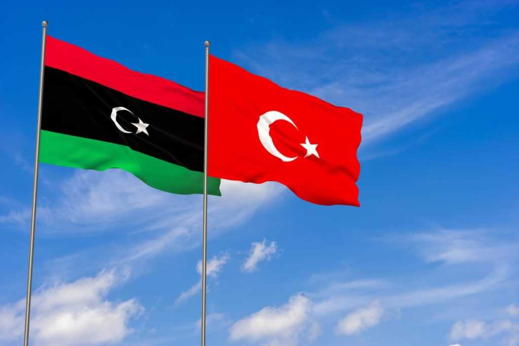 Libya and Turkey flags over blue sky background.