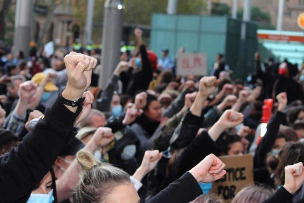 Sydney, NSW / Australia - June 6 2020: Black Lives Matter Protest March. Protesting Aboriginal deaths in custody and the death of George Floyd.  The crowd kneeling with one fist in the air