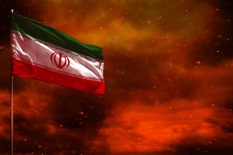 Fluttering Iran flag mockup with blank space for your text on crimson red sky with smoke pillars background. Troubles concept.