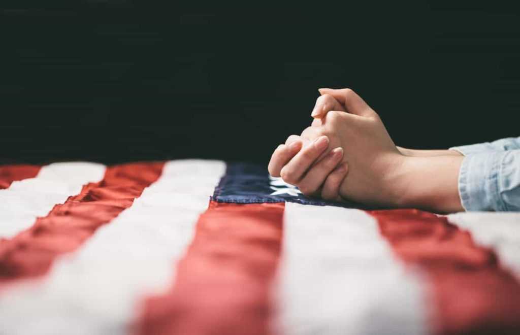 Hands praying over USA flag