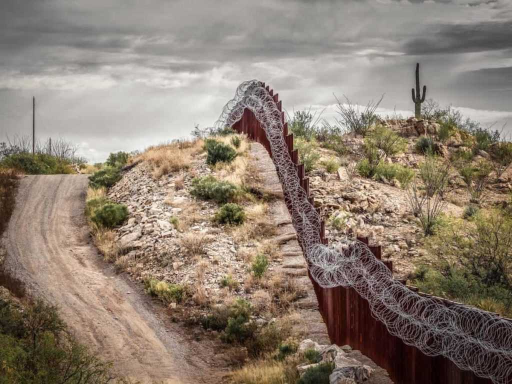 Mexico border wall in southern Arizona with iconic saguaro cactus in background