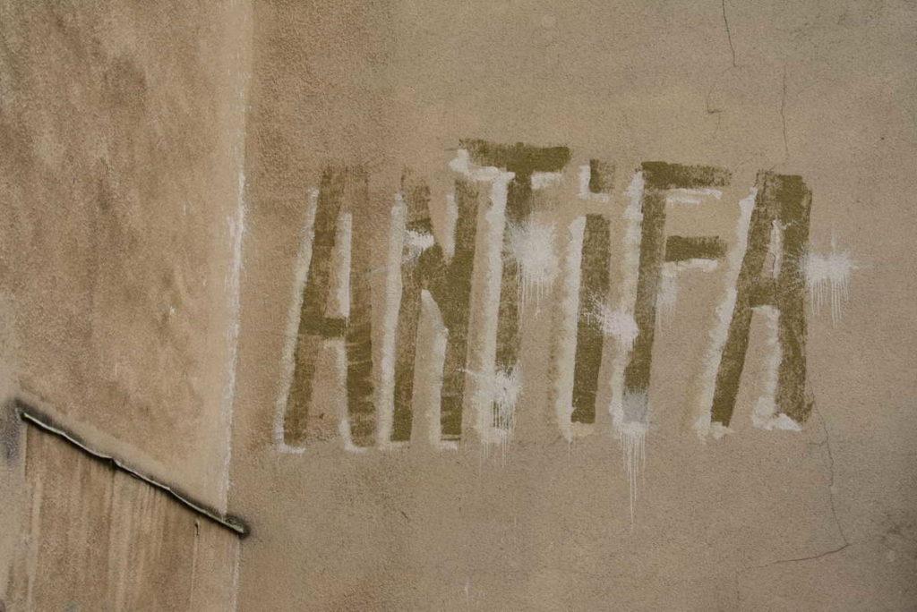 Antifa graffiti on a tan wall in Warsaw Poland