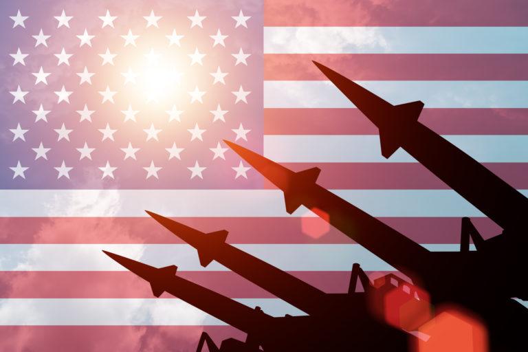 Antiaircraft rockets silhouettes on background of United States of America flag. Sunny.
