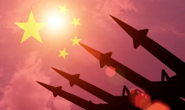 Antiaircraft rockets silhouettes on background of China flag. Sunny.