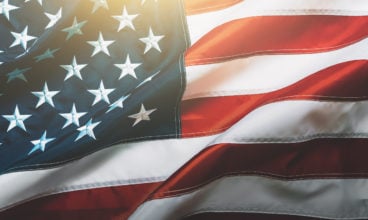USA flag background. Waving American flag in sunlight flare, close up