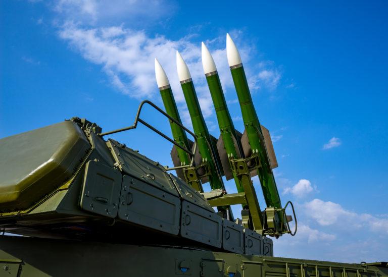 Ballistic missile launcher with four cruise missiles on powerful mobile transportation on background blue sky, antiaircraft forces, military industry