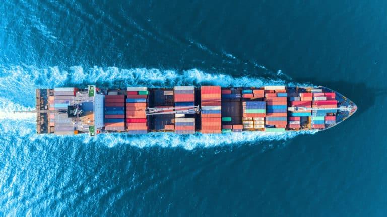 Aerial top view full speed container ship in the sea for logistics import export, shipping or transportation concept.