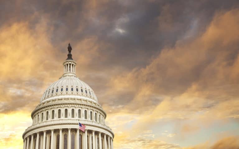 US Capitol dome with American flag and dramatic sky behind